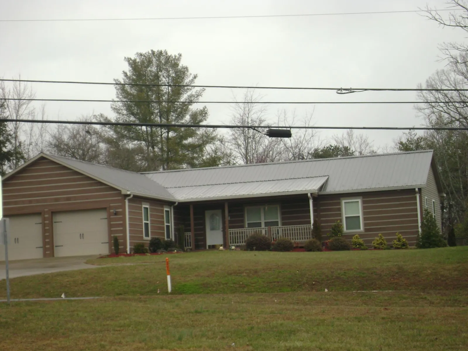 Gray metal roof on a log sided ranch home with a front porch in Westport