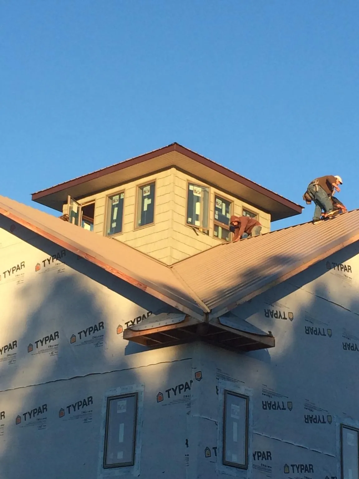 Roofers working around a rooftop cupola on a new metal roof at sunset — Roof Waterproofing in Westport by Roofing Brothers